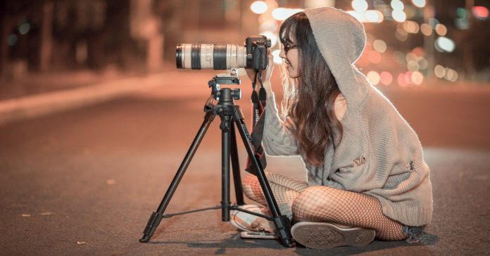 Young woman shooting video at night.