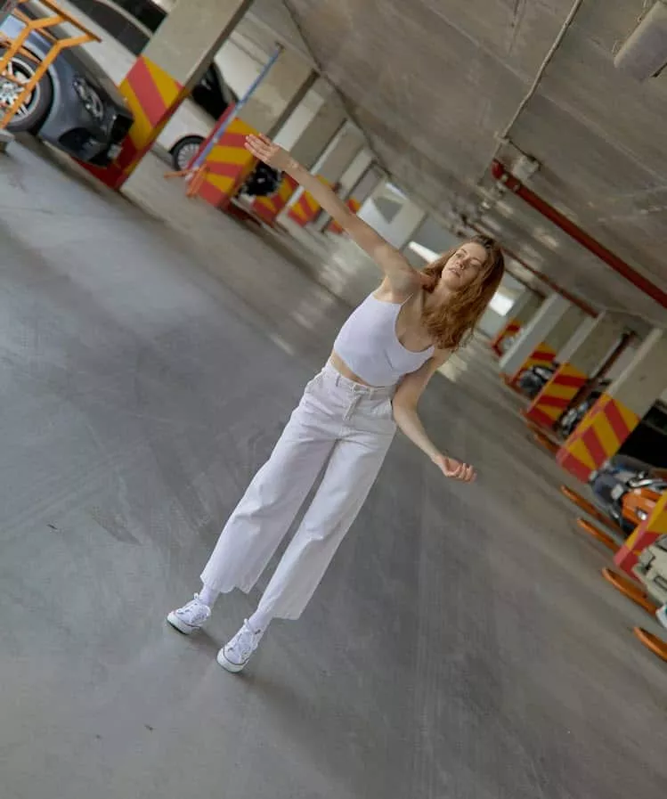 Woman dancing in a car park as an example of a dutch angle shot.