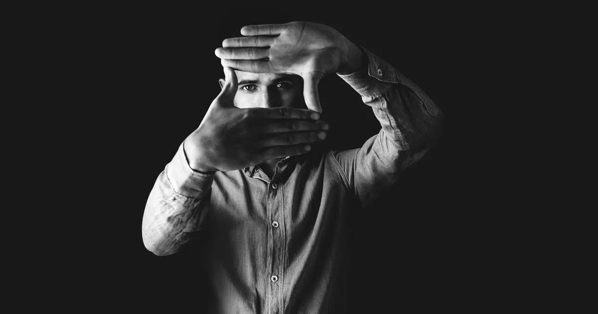 Black and white image of a director framing a shot.