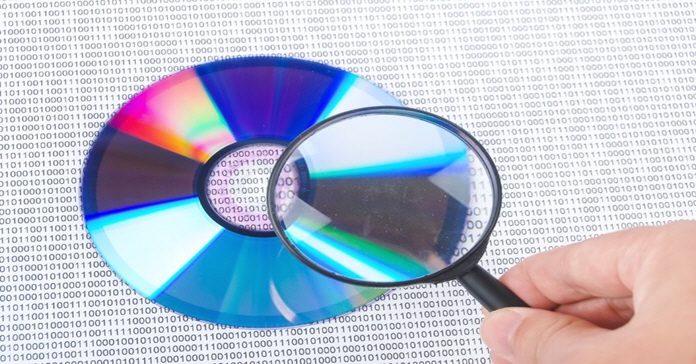 Image of inspecting DVD file structure by holding a magnifying glass over a DVD.