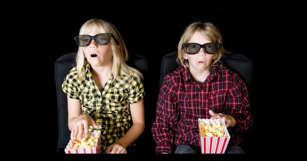 Young girls eating popcorn watching a video.