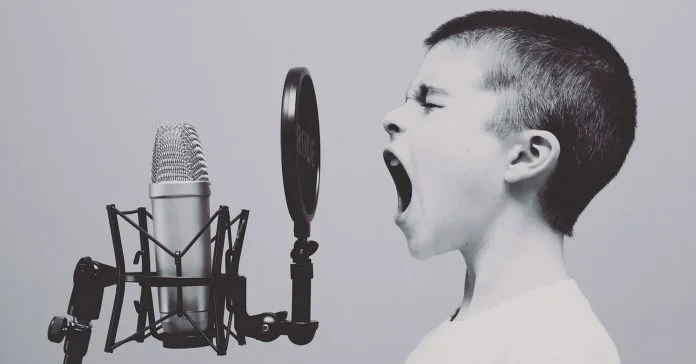 Image of a young boy yelling into a microphone.