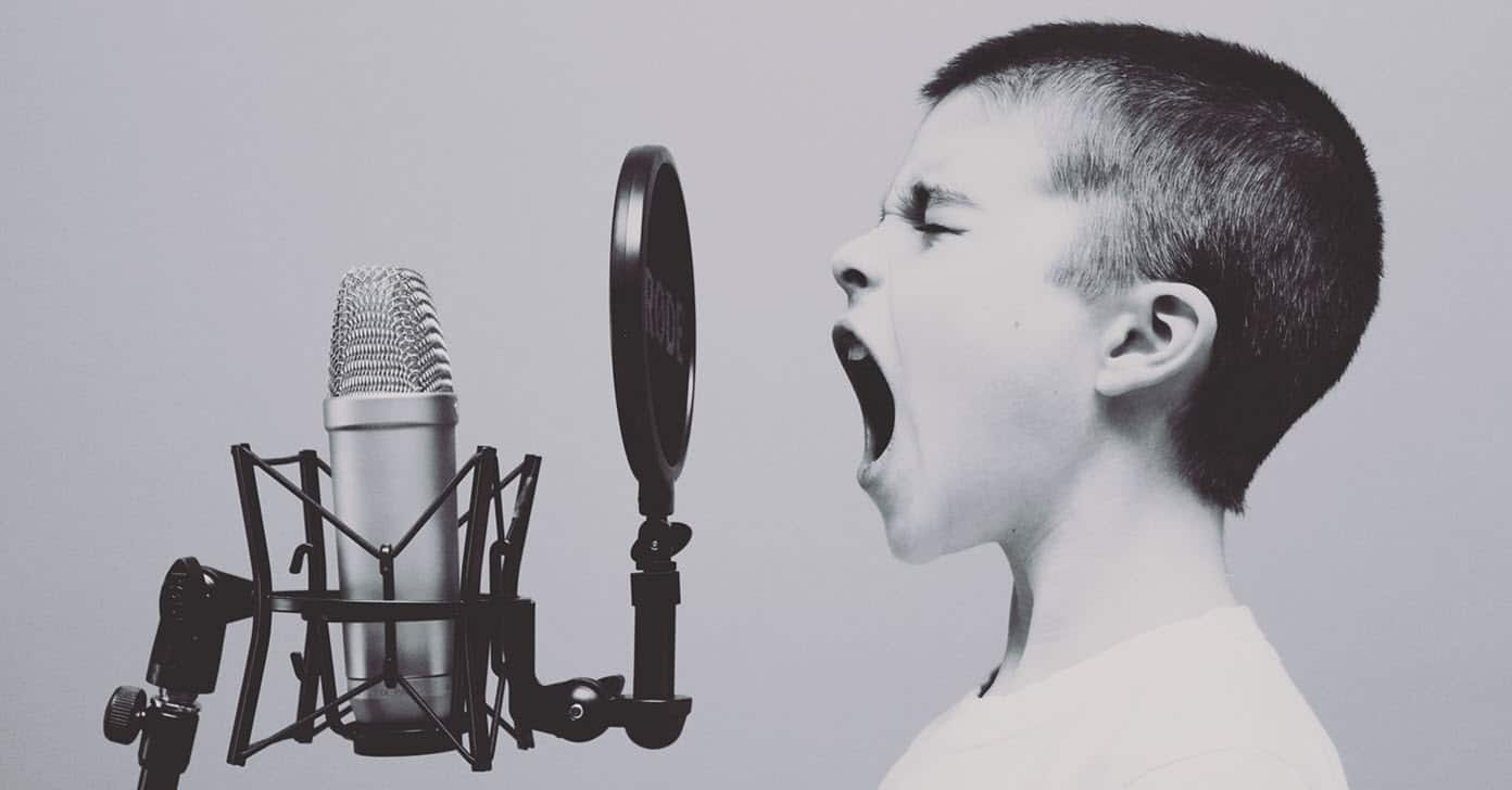Image of a young boy yelling into a microphone.