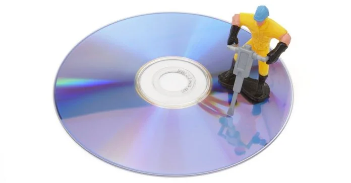 Cartoon mock up of a workman repairing a DVD with a jackhammer.