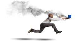 Man running in a panic with a laptop on fire from overheating.