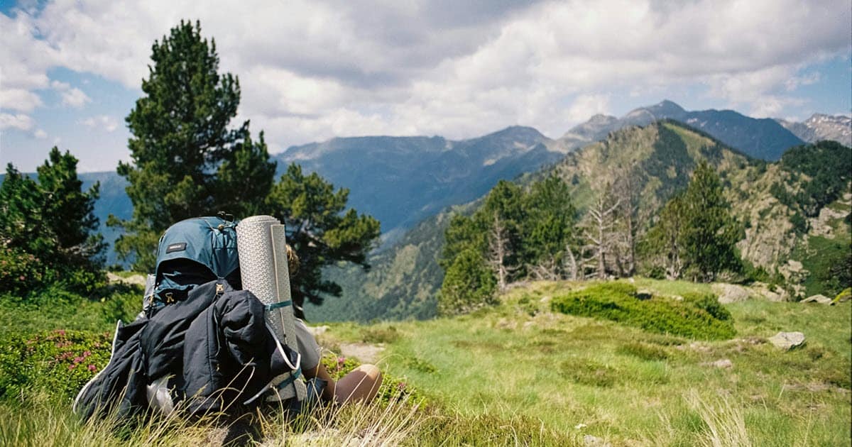 Hiker in a field overlooking mountains example of a wide shot.